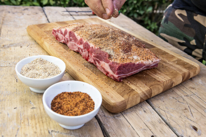 Seasoning raw beef ribs on cutting board