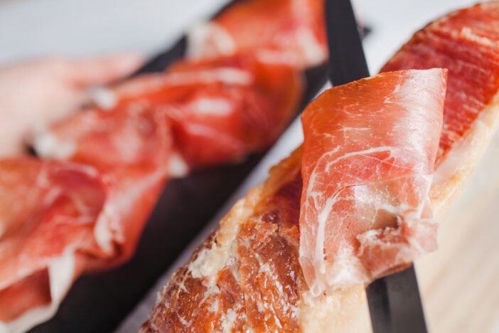 Jamon serrano. Traditional Spanish ham, Slicing of dry-cured ham in Spain