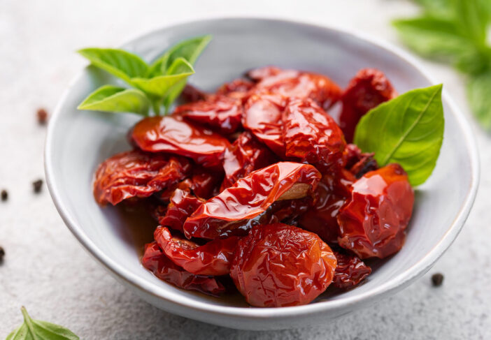 Bowl with homemade sun dried tomatoes with fresh herbs and spices.