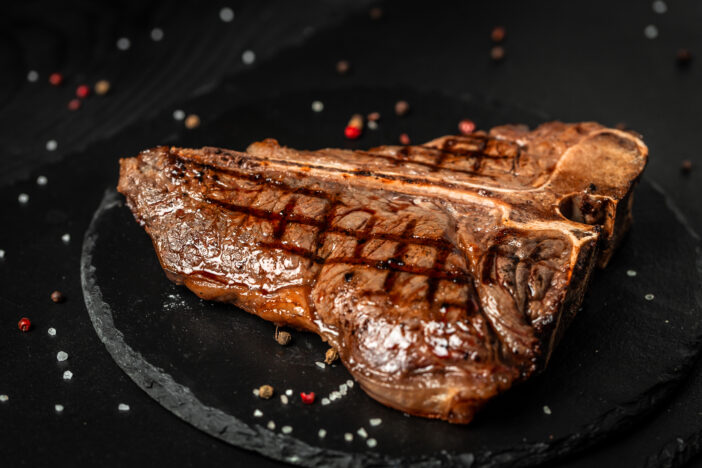 Dry Aged Barbecue Porterhouse Steak T-bone beef steak sliced with large fillet piece with herbs and salt. American meat restaurant.