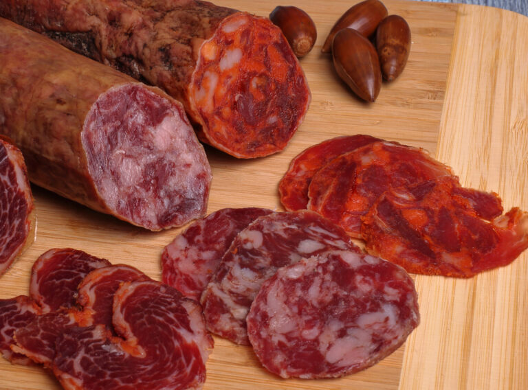 Iberian loin, sausage and chorizo on cutting board, on a gray table and garnished with acorns