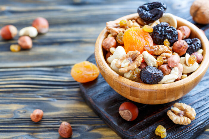 Bowl with a mixture of dried fruit and nuts on an old kitchen table, selective focus.