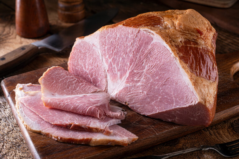 A delicious naturally smoked ham on a rustic wood cutting board.