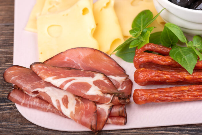 Close-up of cuts of dry-cured pork neck and cheese. Snack plate.