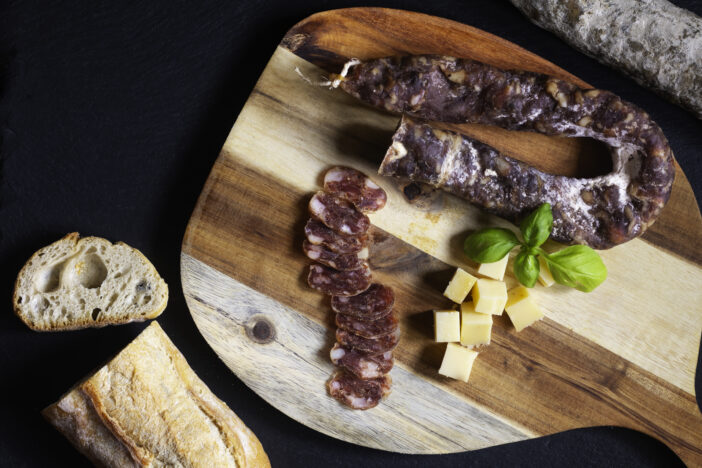 Food concept organic bio Saucisson French  dry-cured salamis or sausages on black slate stone background with copy space