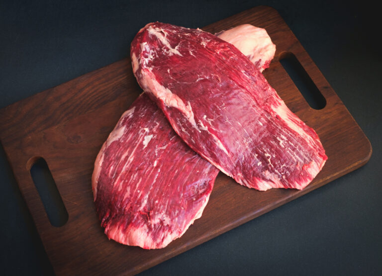 raw flank steak beef on a wooden Board on dark background