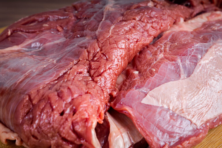 FLANK STEAK beef BBQ food. Raw meat with fat coating on wooden board on gray background. Close view.