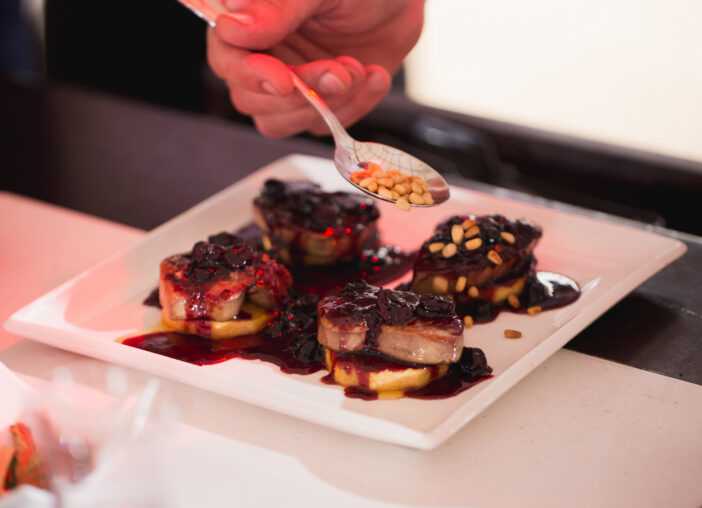 The waiter pours foie gras sauce and sprinkles nuts.