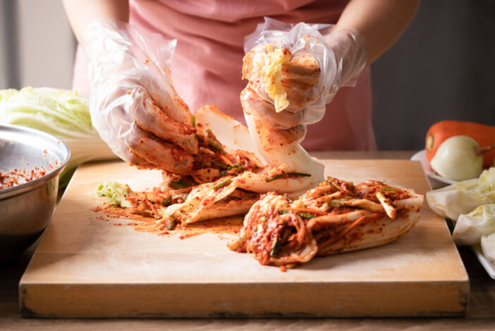 Woman making kimchi cabbage on wooden board, Popular homemade Korean traditional fermented side dish food