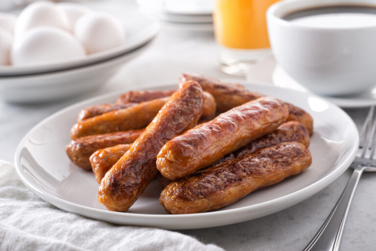 A plate of delicious cooked breakfast sausage with coffee, orange juice and eggs.