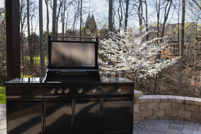 Backyard garden view with a black gas grill in springtime. Outdoors cooking concept.