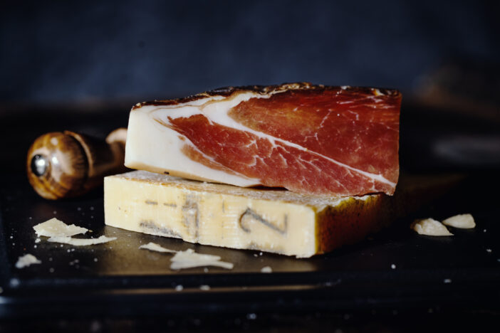 Expensive parmesan cheese with prosciutto meat and knife on wooden board. Italian food concept