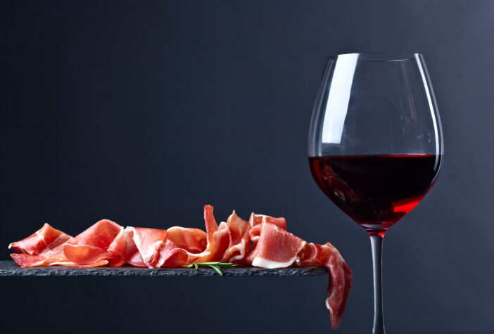 prosciutto with rosemary and glass of red wine on a black  background