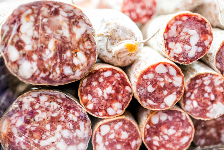 Closeup of sopressata and genoa salami rolls on display in a market shop butcher, price per pound