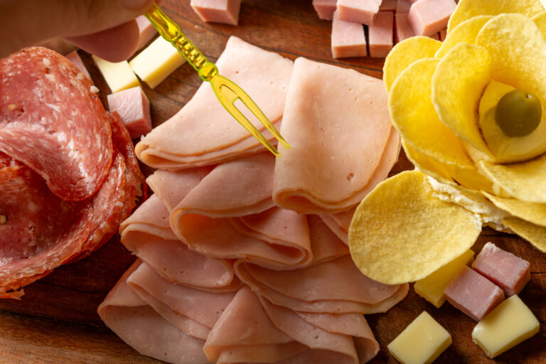 Assorted sliced meats, cheeses, and bread with cutlery