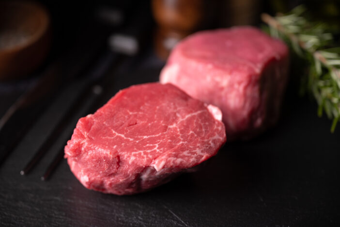 raw tenderloin steak on black stone dish