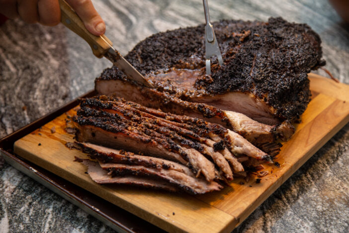 A juicy beef brisket, fresh off the smoker, being sliced on a board on the counter, for a weekend dinner at the cottage. part of series