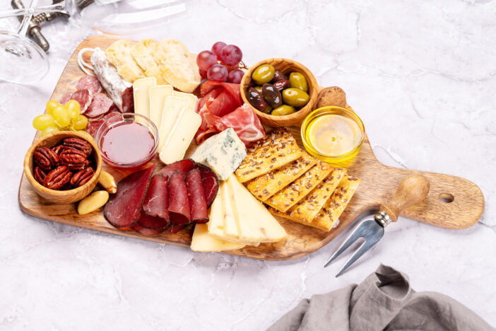 Antipasto board with prosciutto, salami, crackers, cheese, olives and nuts