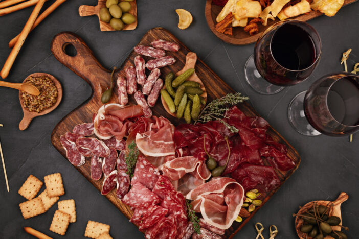 Appetizers table with differents antipasti, charcuterie, snacks and wine. Sausage, ham, tapas, olives, cheese and crackers for buffet party. Top view, flat lay