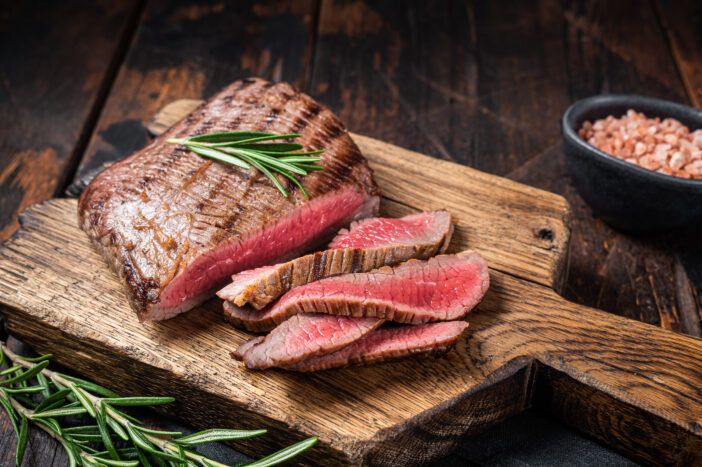 Barbecue dry aged wagyu Flank Steak on a cutting board. Wooden background. Top view.