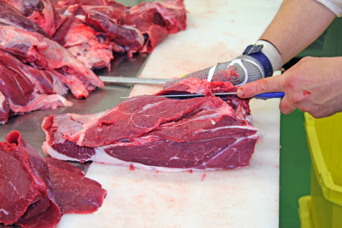 Butcher cutting a fresh beef meat