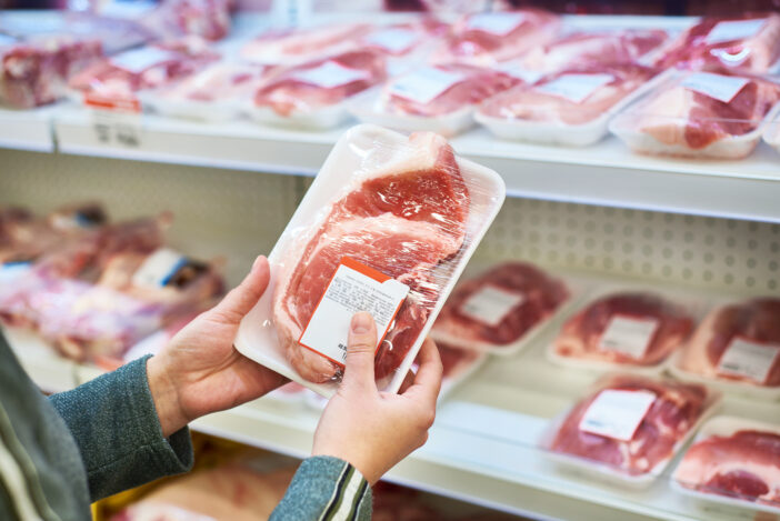 Buyer hands with pork meat packages at the grocery store