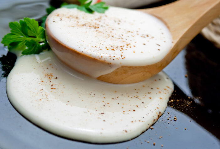 Closeup of bechamel sauce in a wooden spoon