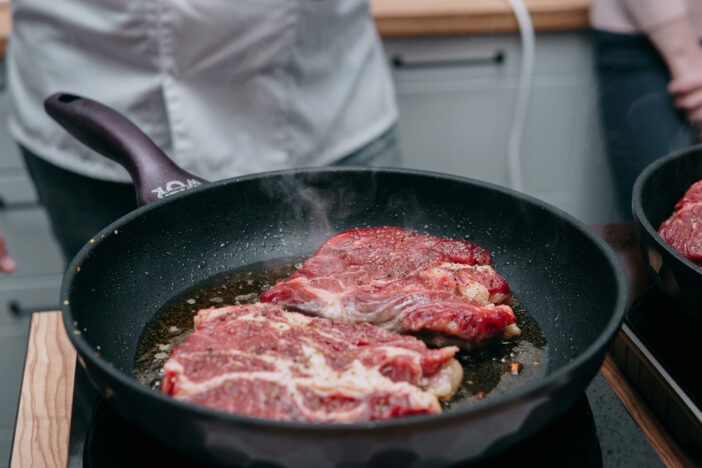 Cooking beef ribeye steak in a frying pan in the cooking class. Steak with spices. Cooking process, close-up.