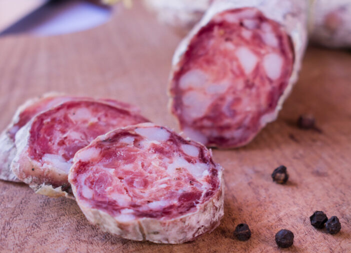 Cured salami sausage, Italian cuisine, isolated on wooden background