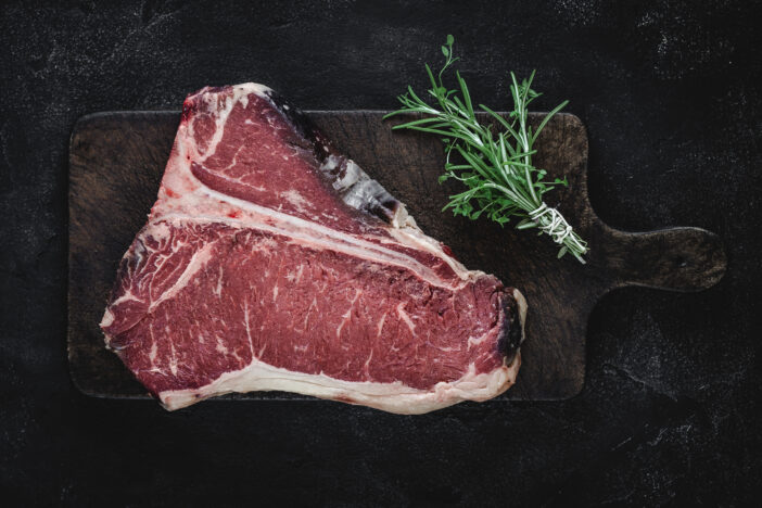 Fresh Raw T-bone Steak Dry Aged for Grill or BBQ on Vintage Brown Cutting Board