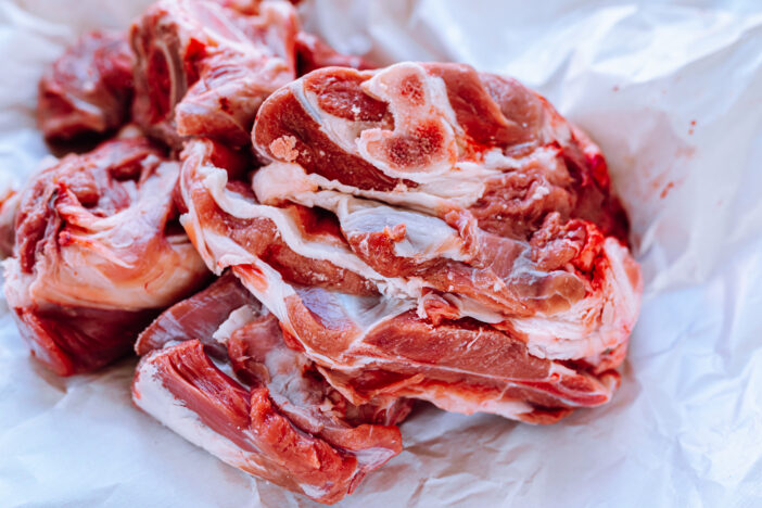 Fresh meat on bone, cut into portions, in an eco-market, on counter, in natural paper packaging