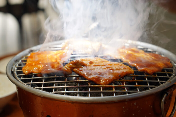 Grilling Raw Sliced Kurobuta Pork over Hot Charcoal Stove, Japanese Barbecue Style called Yakiniku.