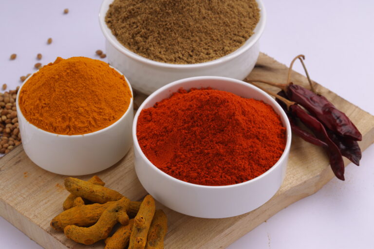 Closeup of Indian spices_Chilli, Turmeric and Coriander  are the basic three spices  used for indian curry or dishes, arranged  in awhite bowls and placed on a wooden base with white texture