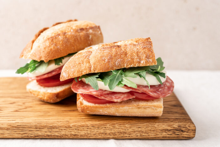 Italian sandwich with baguette, mozzarella, salami and arugula.