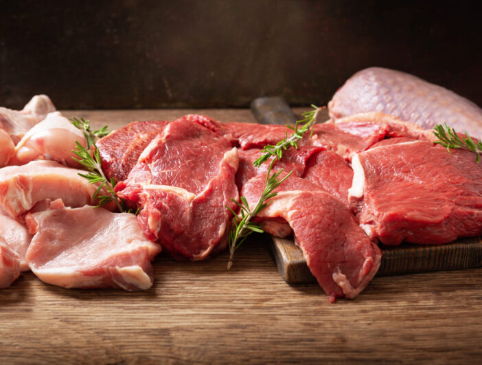 various types of fresh meat: pork, beef, turkey and chicken on a wooden table