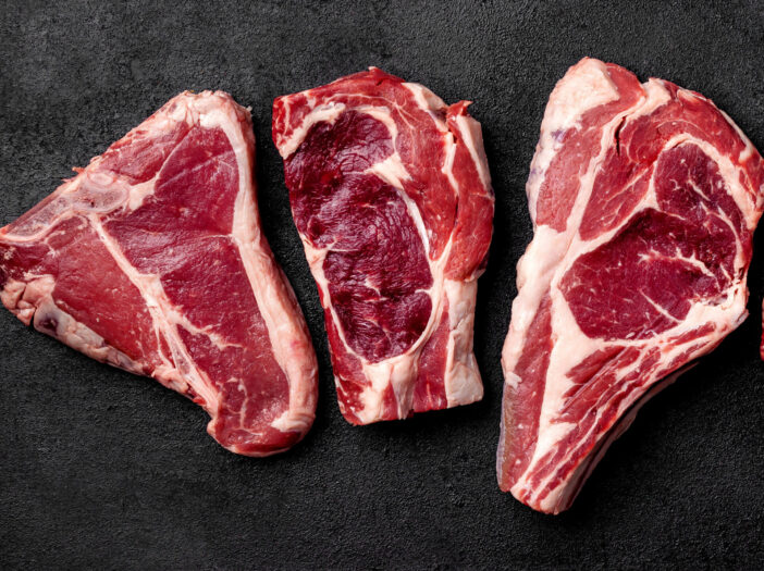 Meat raw steak lies on a black background. side view, copy space, top view