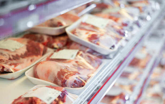 Packaged pork meat displayed on shelves of animal products section of supermarket