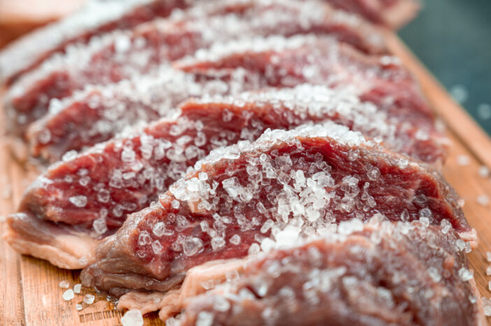 Picanha sliced ​​in pieces, seasoned with coarse salt, on the wooden board