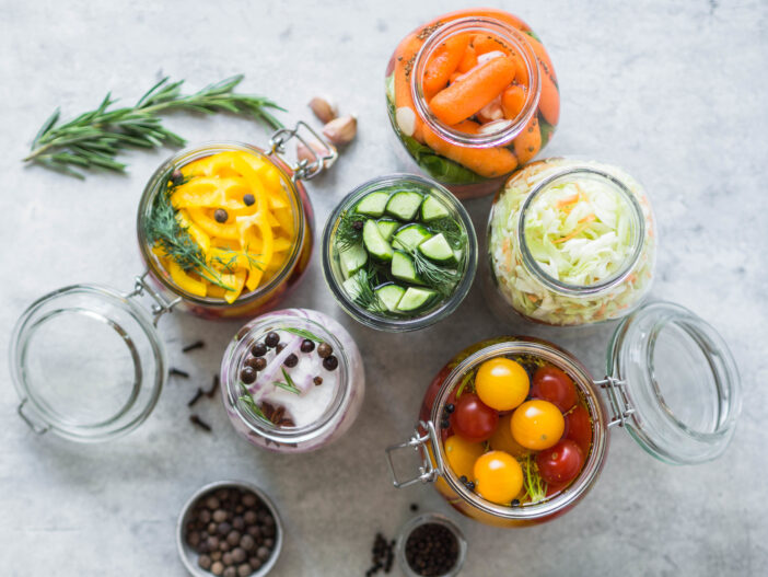 Pickled vegetables. Salting various vegetables in glass jars for long-term storage. Preserves vegetables in glass jars. Variety fermented green vegetables on table.