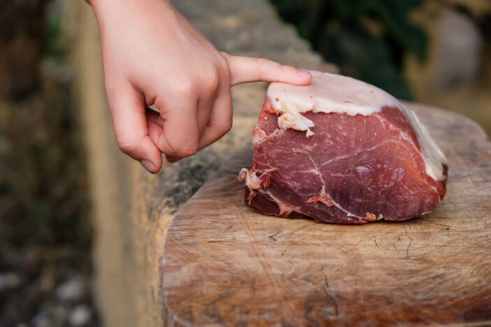 Piece of Spanish ham. Jamón serrano. Child's hand.