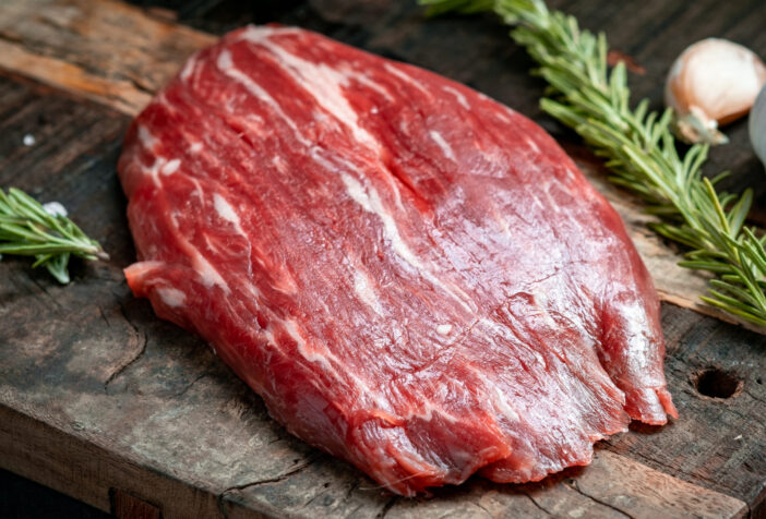 Raw flank beef steak and ingredients for cooking on a wooden Board, close up