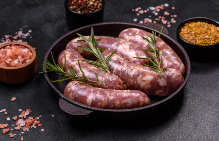 Raw pork sausages grill with spices and herbs on a dark concrete table. Cooking at home