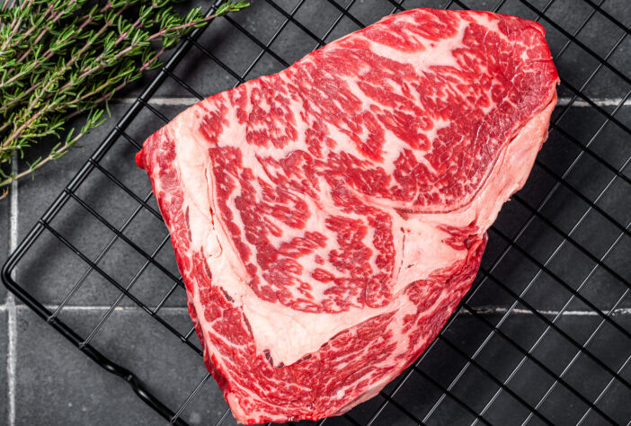 Uncooked wagyu Rib Eye steak, raw  beef meat. Black background. Top view.