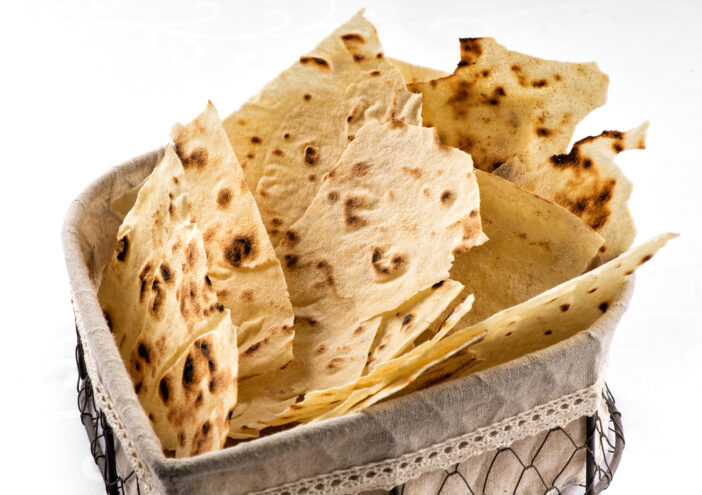 Holder of thin crisp Sardinian Pane Carasau, a traditional flatbread made from durum wheat dough, as an accompaniment to Italian cuisine isolated on white