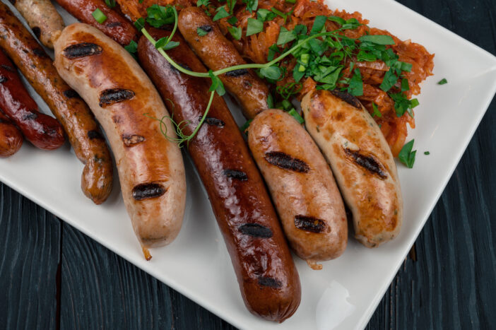 Grilled different sausage with the addition of herbs and horseradish sauce on the plate. Grilling food, bbq, barbecue concept