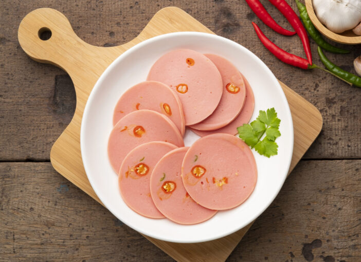 Spicy Sliced Bologna sausage with Chili in white plate.Top view