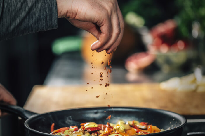 Sprinkling ground red chili pepper paprika over sliced vegetables, motion blur