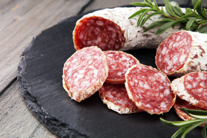 Stone cutting board with sliced salami on it