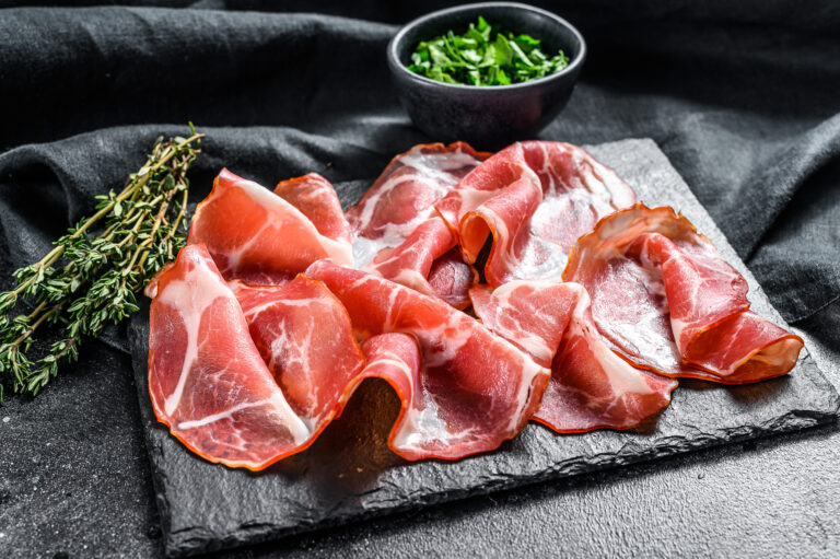 Italian rolled bacon Pancetta Piacentina. Pork meat. Black background. Top view.