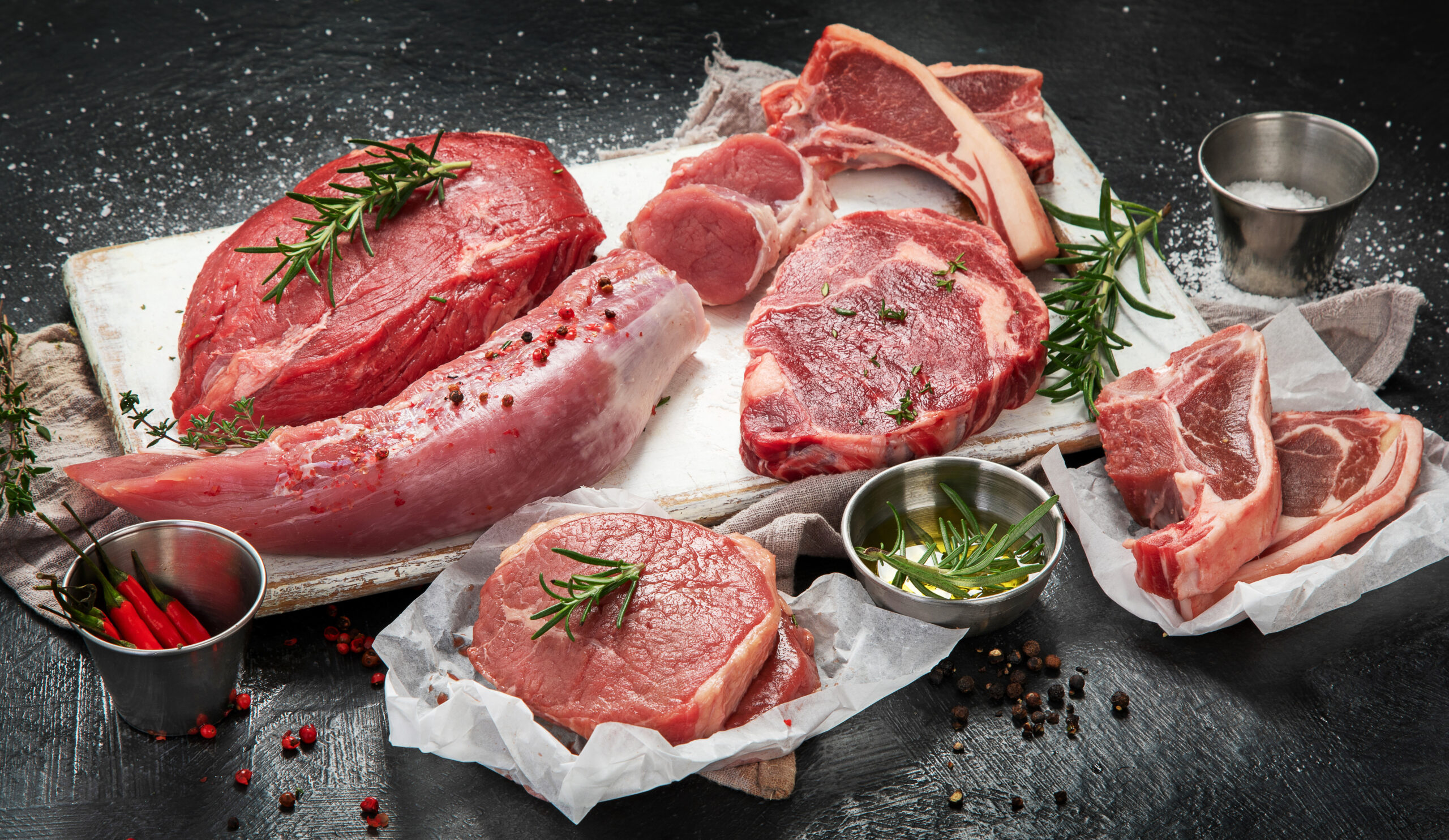 Different types of raw meat - beef, pork, lamb, chicken on dark background.